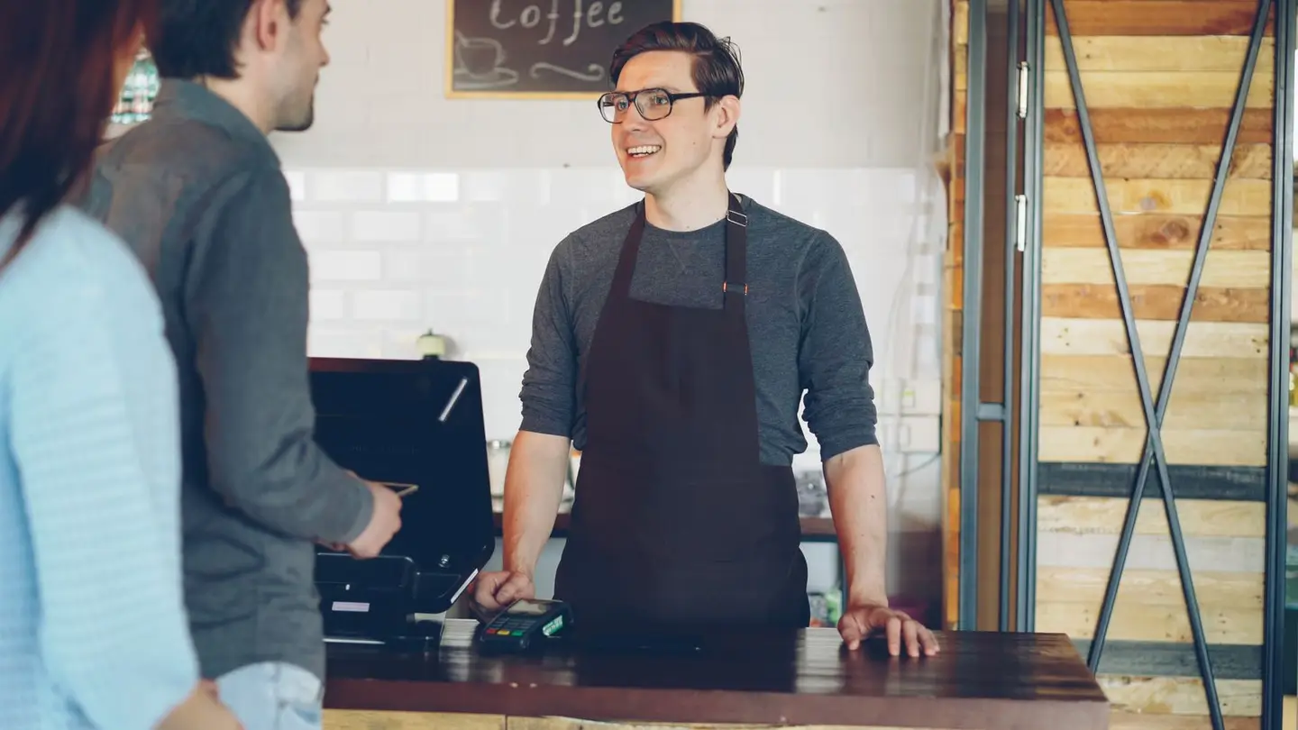 Friendly Barista at Cafe Counter Assisting Customers