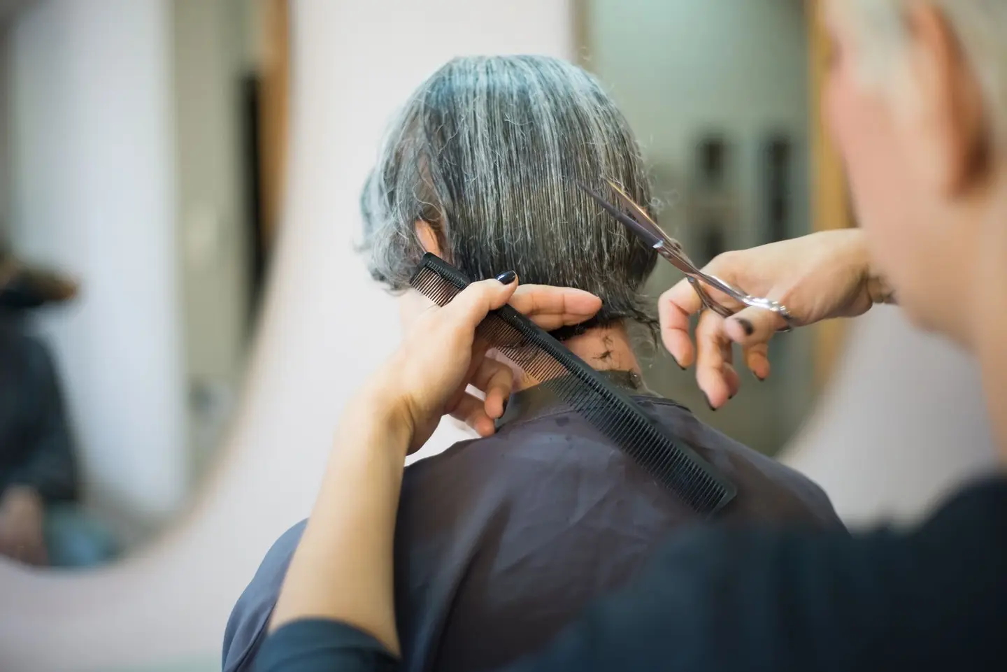 A Client Having Her Hair Cut by the Hair Stylist