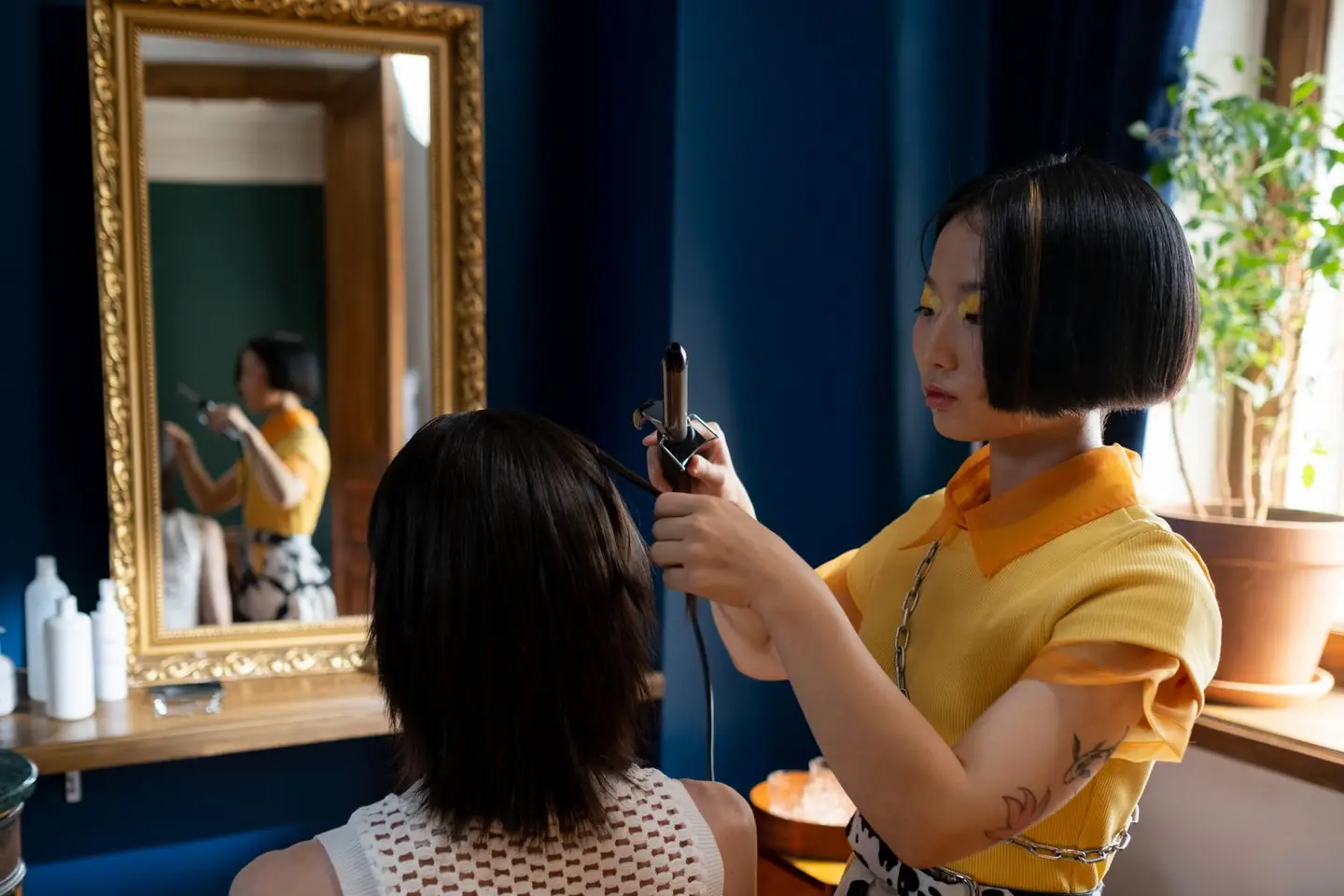 Hairdresser Using Curling Iron on Customers Hair