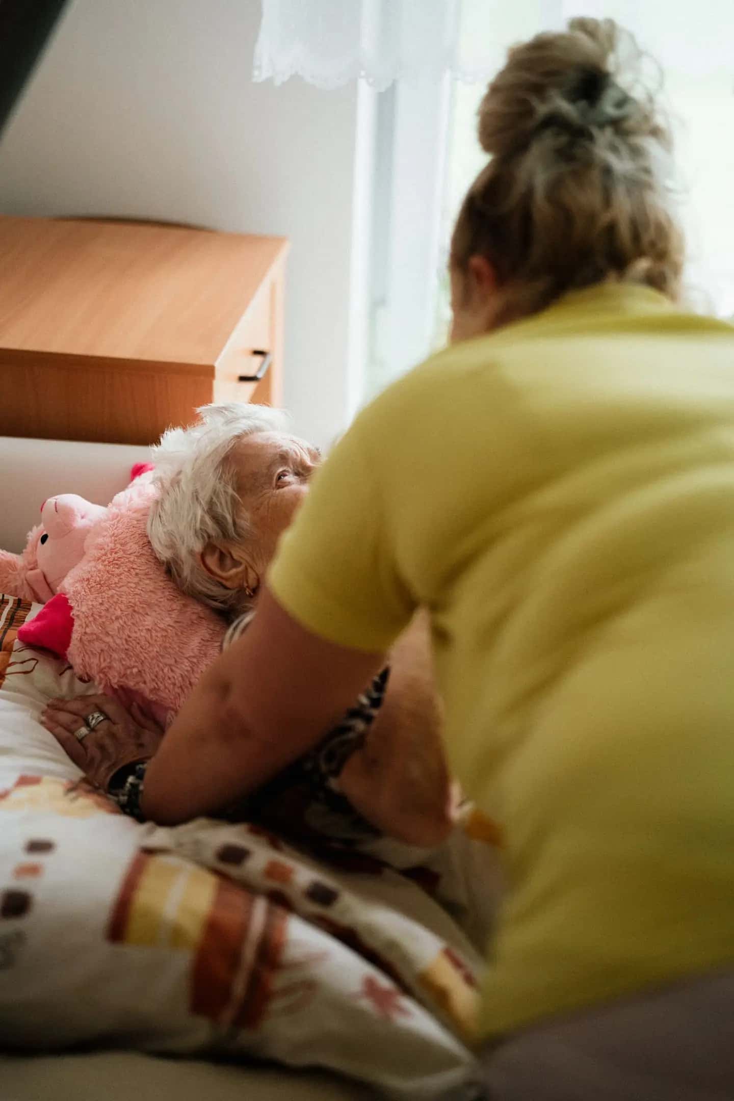 Nurse Bending over Senior in Bed