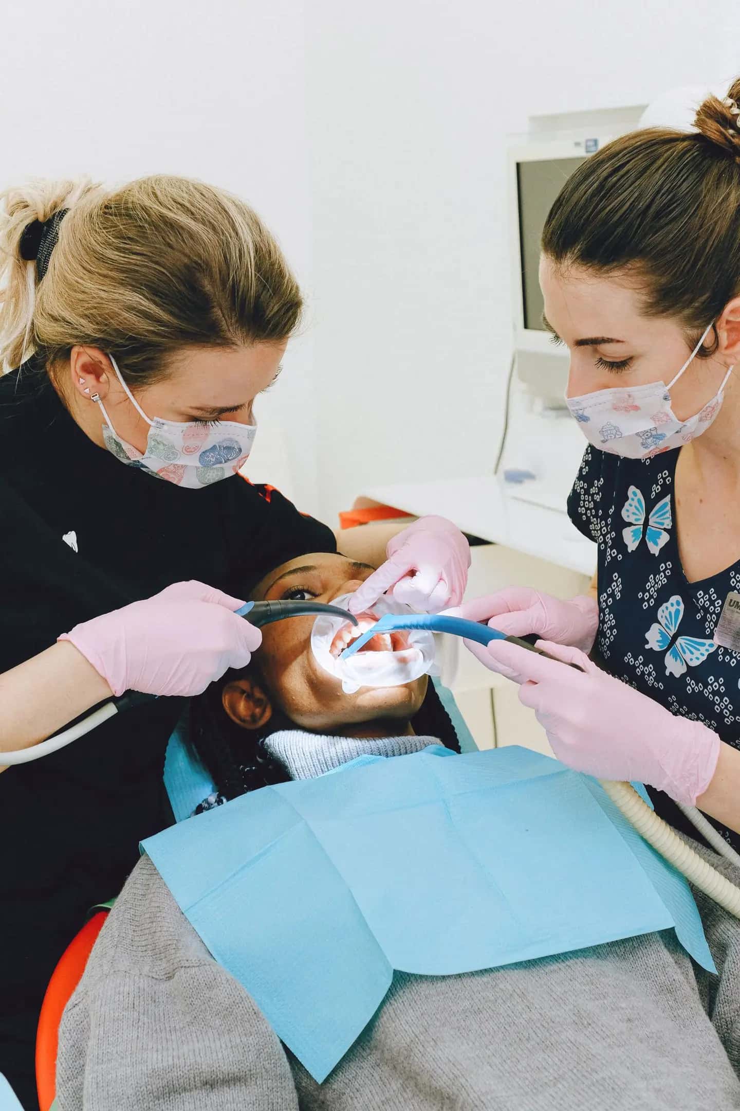 Female dentist with assistant treating patient in clinic