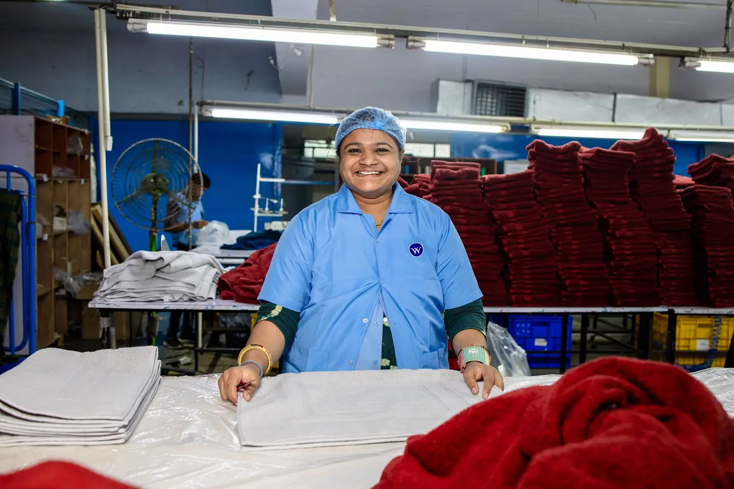 Smiling Factory Worker Arranging Textiles in Warehouse
