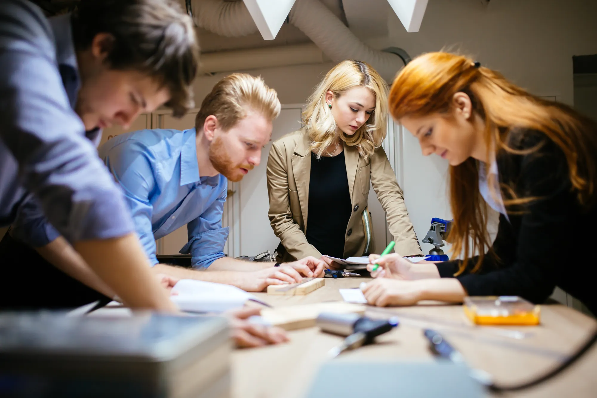 A team leaning over a table, working through a plan on paper