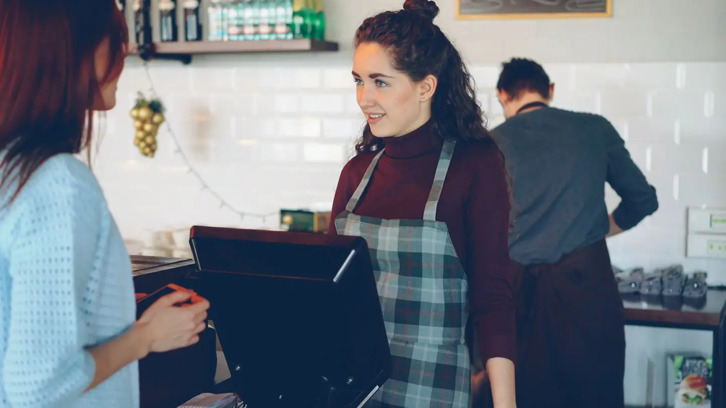 A barista serving a guest at a café counter