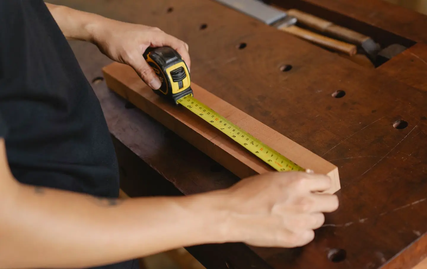 A carpenter measuring a wooden plank